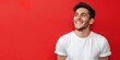 Radiant young man with a hearty laugh and casual style, projecting an aura of joy and confidence against a striking red backdrop.