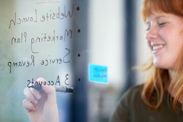 Poster - Happy woman, brainstorming or writing ideas on glass board or sticky note, planning in office. Creative project, agenda or designer in startup for working, strategy and storyboard with goals or smile