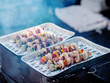 Skewers with sausages and colorful peppers being cooked on a foil tray in a backyard. Summer barbecue easy food concept. Selective focus. Party mood and feel.