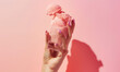 hand holding strawberry ice cream in glass on pastel pink background with copy space