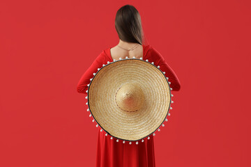 Wall Mural - Beautiful woman with sombrero hat and dress on red background, back view