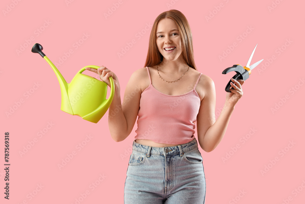 Young woman with watering can and secateurs on pink background