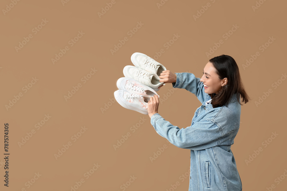 Beautiful young woman with different stylish sneakers on beige background