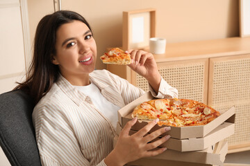 Poster - Young woman eating piece of tasty pizza and holding cardboard boxes at home