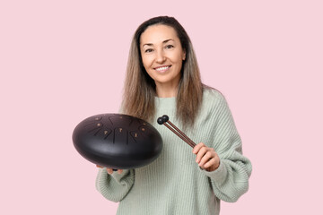 Poster - Beautiful mature woman with glucophone and sticks on pink background