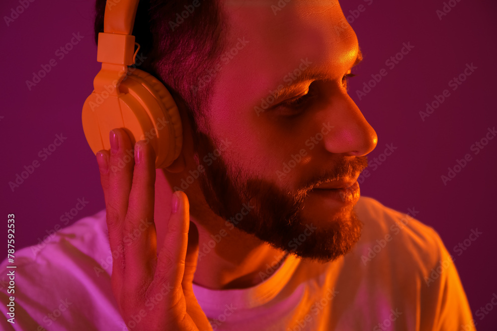 Young man in modern headphones on purple background, closeup