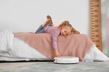 Poster - Cute little girl with robot vacuum cleaner on carpet in bedroom