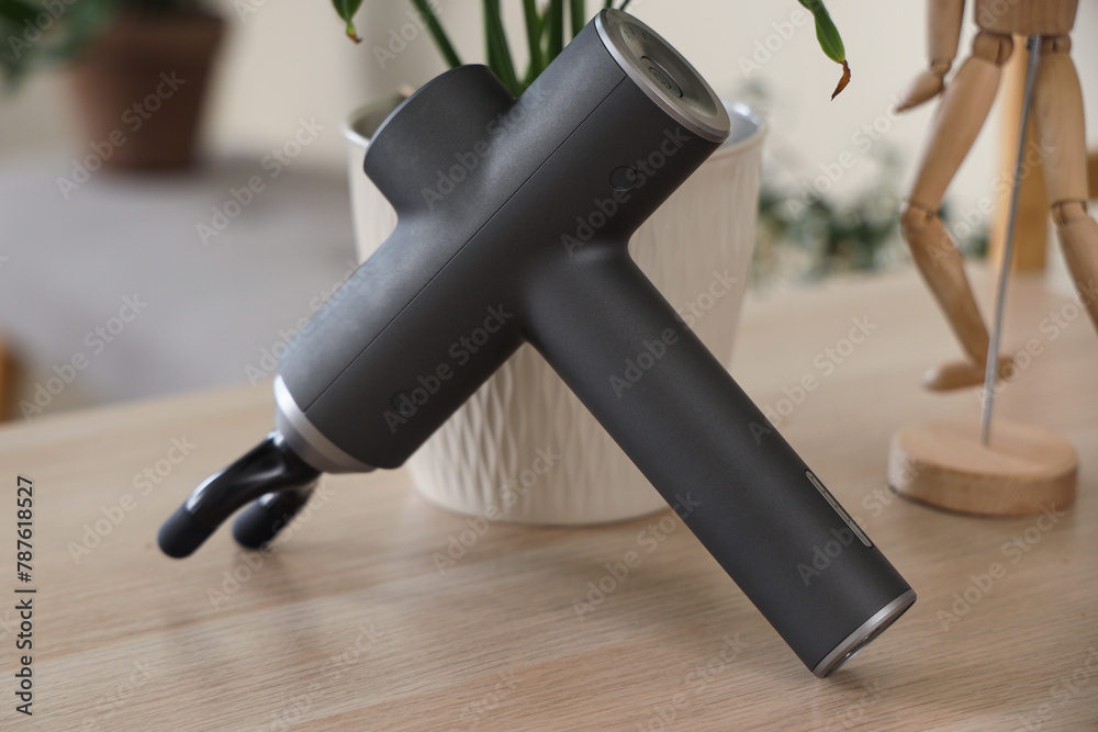 Percussive massager on table in room, closeup