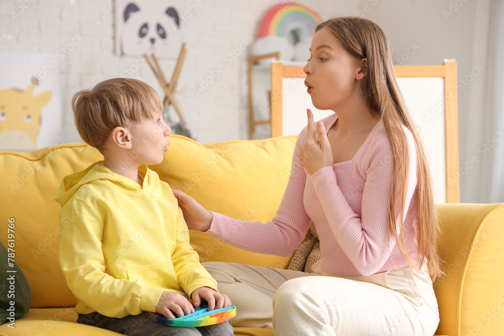 Female psychologist working with little boy on sofa in office. World Autism Awareness Day