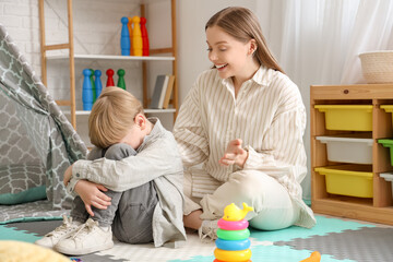 Wall Mural - Female psychologist working with stressed little boy in office. World Autism Awareness Day