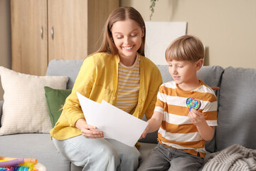 Sticker - Female psychologist working with little boy on sofa in office. World Autism Awareness Day