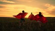 Child imagine being comic book heroes running across meadow in red capes. Children in red capes run across field pretending to be superheroes. Kids actively spend evening dressed as superheroes, dream