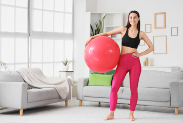 Poster - Sporty young woman with fitness ball at home