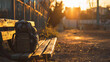 A student's school bag placed on a bench in a deserted playground during golden hour.