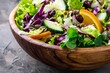 Close up of a wooden bowl with fresh vegetable salad containing mixed greens cabbage kale spinach orange apple seeds cranberries and raisins