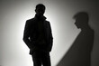 The image depicts a man standing confidently with his shadow cast on the wall, creating an air of mystery and concealment