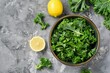 Fresh kale leaves in a bowl with lemon on gray background top view Making kale salad