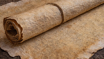 Wall Mural - An aged papyrus manuscript, unrolled, displaying a textured surface with dark spots on a wooden background.