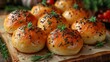   A tight shot of several bread rolls, each topped with a sprig of rosemary, arranged on a sheet of parchment paper