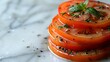   A stack of sliced tomatoes on a pristine white countertop, adjacent to a mound of seasonings
