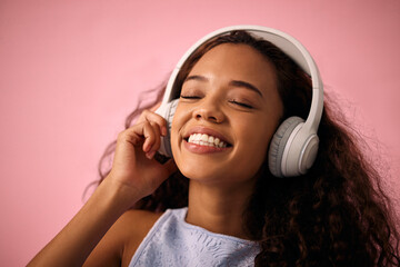 Poster - Happy girl, relax and listening to music with headphones for jazz or beats on a pink studio background. Female person enjoying podcast, audio streaming or sound with smile for radio, song or playlist