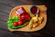 Pork loin baked in sauce with fried potatoes on dark boards background. Menu for a pub
