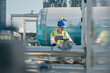 © ultramansk - Construction engineer on a rooftop checking HVAC systems, with urban skyline in the distance