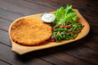 Chicken schnitzel in breading with green beans on dark boards background. Menu for a pub