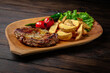 Pork or beef steak with arena potatoes on dark boards background. Menu for a pub