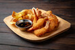Battered king prawns with barbecue sauce and potato chips on dark boards background. Menu for a pub