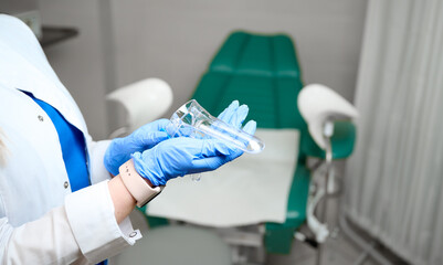 Pretty female doctor gynecologist in blue medical sterile gloves holding vaginal speculum. Women's health. Prevention illness. Early detection of cancer. Close up