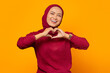 © Bangun Stock Photo - Smiling young girl in red sweater showing heart with two hands,