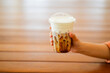 © padarn - Close up and selective focus hand of woman holding a take-out iced espresso with cream foam at cafe, isolate concept