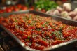 Tomato sauce with finely chopped herbs spread on a tray against a blurred background of kitchen ingredients