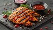 Grilled chicken Tabaka with sauce on stone plate.