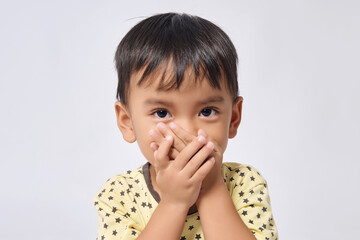 Wall Mural - Portrait asian boy standing and used two hands closed his mouth and looking at camera on white background