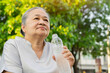 Old Asian woman drinks water after walking exercise in the park.