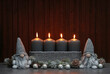 
Christmas and Advent decoration: elves in front of a dark wooden background with four burning candles and copy space.