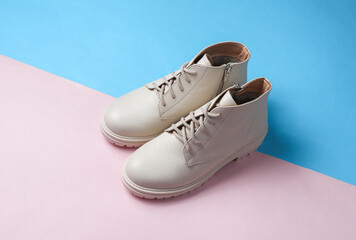 Wall Mural - Women's white leather winter boots on a blue-pink background.