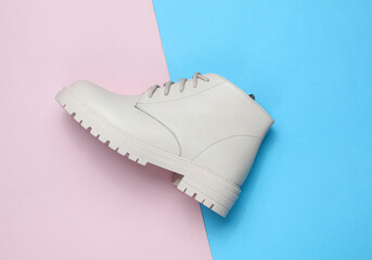 Wall Mural - Women's white leather winter boot on a blue-pink background. Top view