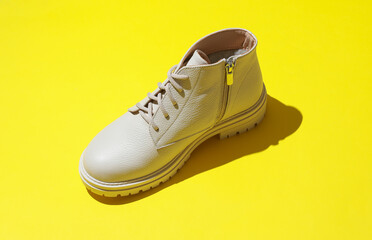 Wall Mural - Women's white leather winter boot on a yellow background.