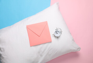 Sticker - White pillow with envelope and alarm clcok on a blue-pink pastel background. Top view