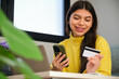 Latin female teenager with braces buying online in a smartphone with a credit card.
