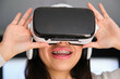 Female Latin teenager with braces using virtual reality glasses at home.