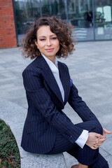 Wall Mural - Successful woman dressed in an elegant suit, posing in front of the office. Female business leader.