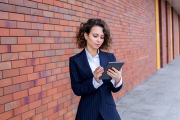 Wall Mural - Successful woman dressed in an elegant suit, posing in front of the office. Female business leader.