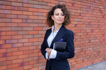 Wall Mural - Successful woman dressed in an elegant suit, posing in front of the office. Female business leader.