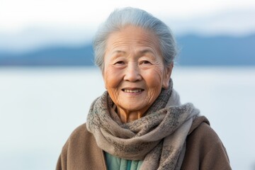 Wall Mural - Portrait of a happy asian elderly woman in her 90s showing off a thermal merino wool top isolated in calm bay background