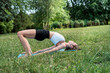 Young beautiful woman doing pilates or streching exercise in morning park