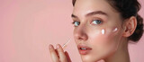 Fototapeta  - Young beautiful girl model holds facial make-up cosmetic serum in her hand and drops it onto her face with a pipette on a minimalist pastel pink background created with Generative AI Technology